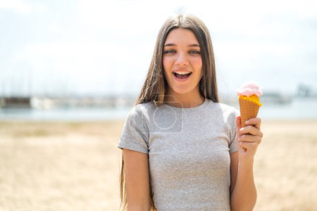 Téléchargez les photos : Adolescente avec une crème glacée cornet à l'extérieur avec une expression faciale surprise et choquée - en image libre de droit