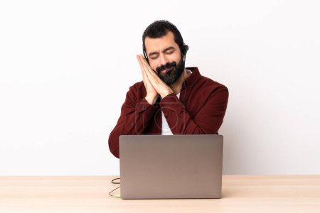 Téléchargez les photos : Télévendeur caucasien homme travaillant avec un casque et avec ordinateur portable faisant geste de sommeil dans l'expression dorable. - en image libre de droit