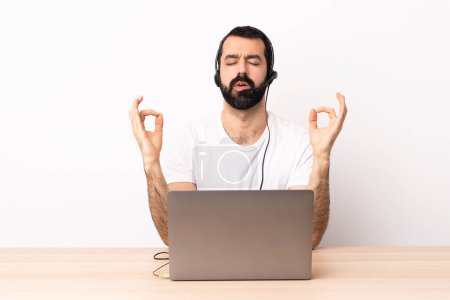 Téléchargez les photos : Télévendeur caucasien homme travaillant avec un casque et avec ordinateur portable dans la pose zen. - en image libre de droit
