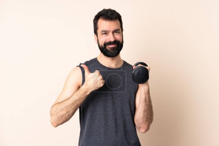Téléchargez les photos : Homme de sport caucasien avec barbe faisant haltérophilie sur fond isolé donnant un pouce geste - en image libre de droit