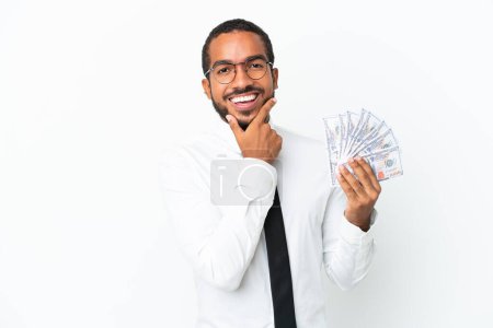 Foto de Joven hombre latino de negocios tomando un montón de dinero aislado sobre fondo blanco feliz y sonriente - Imagen libre de derechos