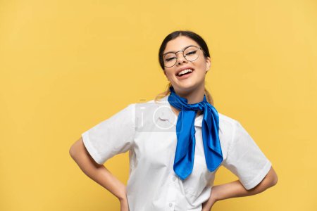 Photo for Airplane stewardess isolated on yellow background posing with arms at hip and smiling - Royalty Free Image