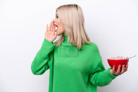 Photo for Young Russian woman holding a bowl of cereals isolated on white background shouting with mouth wide open to the side - Royalty Free Image