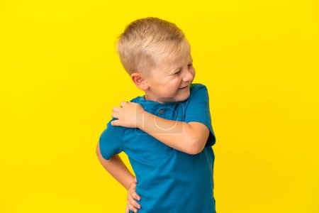 Photo for Little Russian boy isolated on yellow background suffering from pain in shoulder for having made an effort - Royalty Free Image