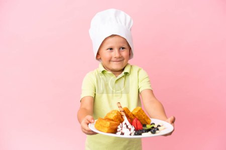 Photo for Little Russian boy holding waffles over isolated background - Royalty Free Image