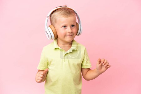 Foto de Pequeño chico ruso escuchando música con auriculares sobre un fondo aislado - Imagen libre de derechos
