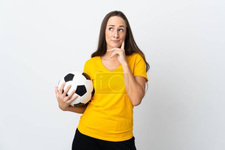 Téléchargez les photos : Jeune joueur de football femme sur fond blanc isolé ayant des doutes et la pensée - en image libre de droit