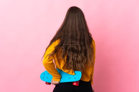 Photo for Young hispanic woman over isolated pink background with a skate in back position - Royalty Free Image