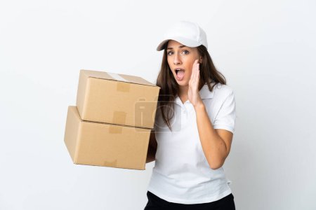 Photo for Young delivery woman over isolated white background whispering something with surprise gesture while looking to the side - Royalty Free Image