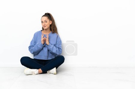 Téléchargez les photos : Jeune femme assise sur le sol complotant quelque chose - en image libre de droit