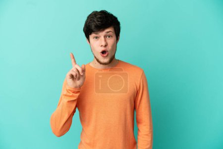 Téléchargez les photos : Jeune homme russe isolé sur fond bleu dans le but de réaliser la solution tout en levant le doigt - en image libre de droit
