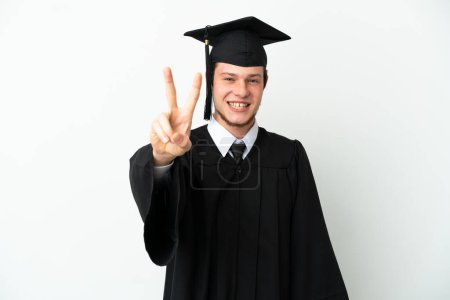 Foto de Universidad joven ruso graduado aislado sobre fondo blanco sonriendo y mostrando signo de victoria - Imagen libre de derechos