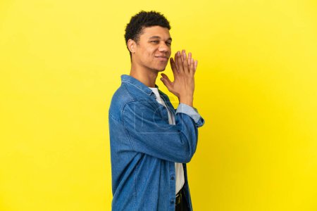 Téléchargez les photos : Jeune homme afro-américain isolé sur fond jaune complotant quelque chose - en image libre de droit