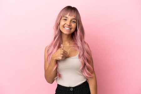 Foto de Joven mujer de raza mixta con el pelo rosa aislado sobre fondo rosa dando un gesto pulgar hacia arriba - Imagen libre de derechos