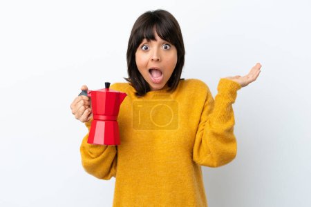 Photo for Young mixed race woman holding coffee pot isolated on white background with shocked facial expression - Royalty Free Image