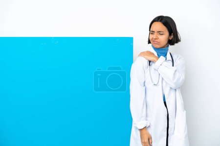 Téléchargez les photos : Jeune femme médecin métis avec une grande pancarte isolée sur fond blanc souffrant de douleur à l'épaule pour avoir fait un effort - en image libre de droit