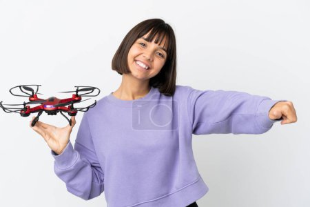 Photo for Young mixed race woman holding a drone isolated on white background giving a thumbs up gesture - Royalty Free Image
