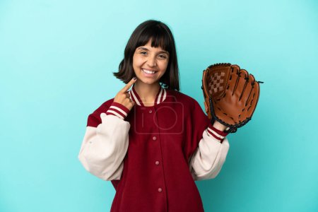 Foto de Joven mujer jugador de raza mixta con guante de béisbol aislado sobre fondo azul dando un gesto pulgar hacia arriba - Imagen libre de derechos
