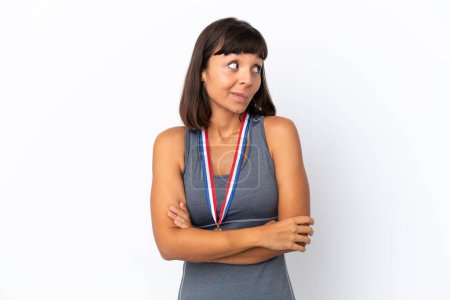 Photo for Young mixed race woman with medals isolated on white background making doubts gesture while lifting the shoulders - Royalty Free Image
