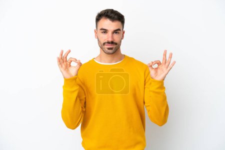 Téléchargez les photos : Jeune homme caucasien isolé sur fond blanc montrant ok signe avec deux mains - en image libre de droit