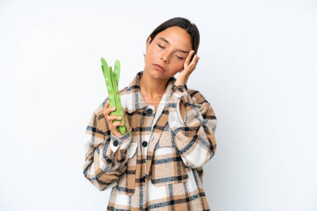 Photo for Young hispanic woman holding a green beans isolated on white background with headache - Royalty Free Image