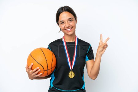Foto de Young basketball player woman isolated on white background smiling and showing victory sign - Imagen libre de derechos