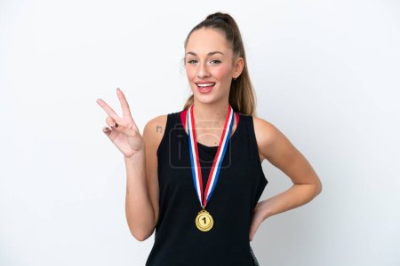 Téléchargez les photos : Jeune femme caucasienne avec des médailles isolées sur fond blanc souriant et montrant signe de victoire - en image libre de droit