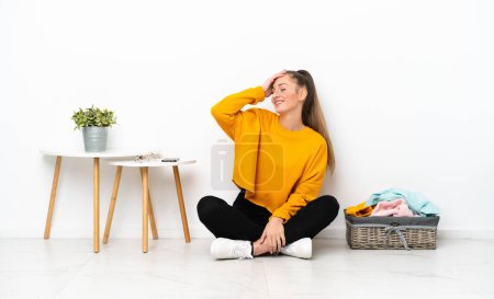 Photo for Young caucasian woman folding clothes sitting on the floor isolated on white background has realized something and intending the solution - Royalty Free Image