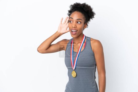 Photo for Young African American woman with medals isolated on white background listening to something by putting hand on the ear - Royalty Free Image
