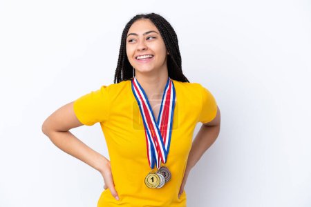 Photo for Teenager girl with braids and medals over isolated pink background posing with arms at hip and smiling - Royalty Free Image
