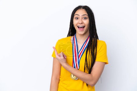 Photo for Teenager girl with braids and medals over isolated pink background surprised and pointing side - Royalty Free Image