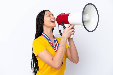 Photo for Teenager girl with braids and medals over isolated pink background shouting through a megaphone - Royalty Free Image