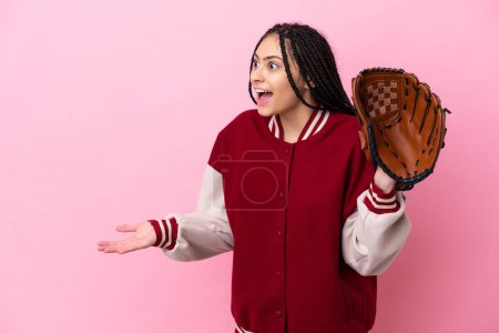 Foto de Jugador adolescente con guante de béisbol aislado sobre fondo rosa con expresión sorpresa mientras mira al lado - Imagen libre de derechos