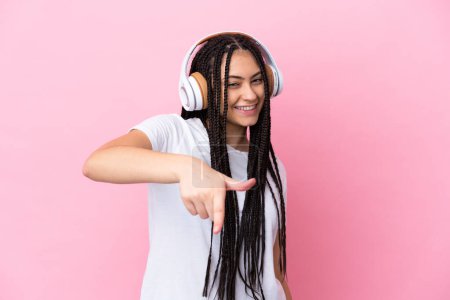 Téléchargez les photos : Adolescente avec des tresses sur fond rose isolé écouter de la musique - en image libre de droit