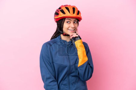 Foto de Adolescente ciclista chica aislado en rosa fondo pensando en una idea mientras mira hacia arriba - Imagen libre de derechos