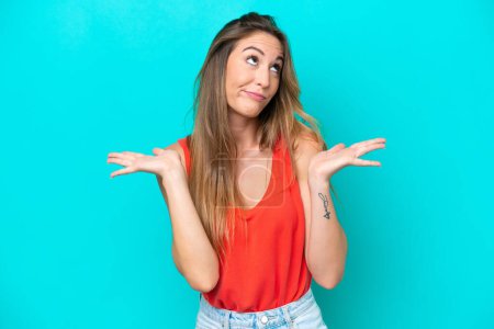 Photo for Young caucasian woman isolated on blue background making doubts gesture - Royalty Free Image