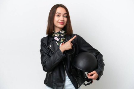 Téléchargez les photos : Jeune femme ukrainienne avec un casque de moto isolé sur fond blanc pointant vers le côté pour présenter un produit - en image libre de droit