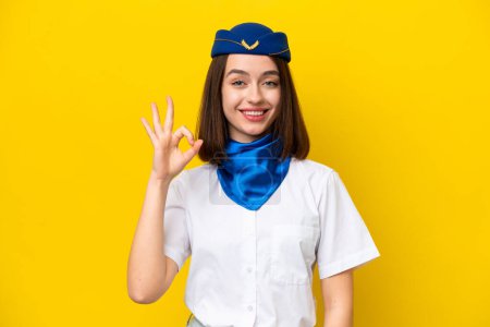Photo for Airplane stewardess Ukrainian woman isolated on yellow background showing ok sign with fingers - Royalty Free Image