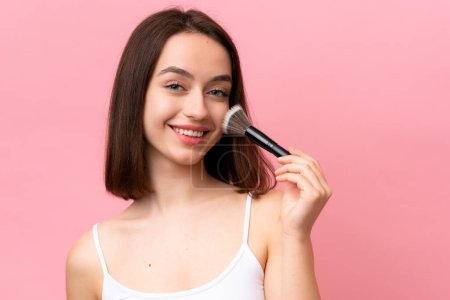 Photo for Young Ukrainian woman isolated on pink background holding makeup brush and whit happy expression - Royalty Free Image