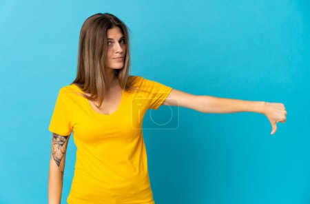 Photo for Young slovak woman isolated on blue background showing thumb down with negative expression - Royalty Free Image