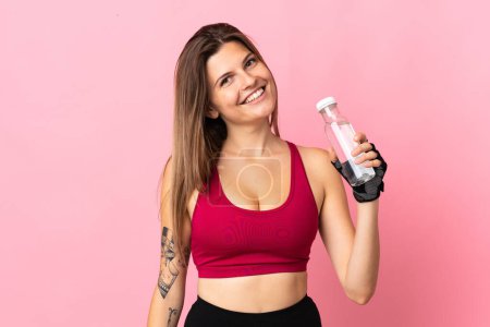 Foto de Mujer joven eslovaca aislada sobre fondo rosa con botella de agua deportiva - Imagen libre de derechos