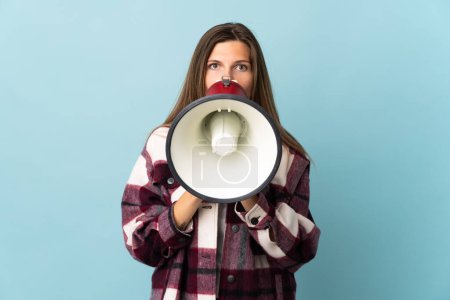 Téléchargez les photos : Jeune femme slovaque isolée sur fond bleu criant à travers un mégaphone pour annoncer quelque chose - en image libre de droit