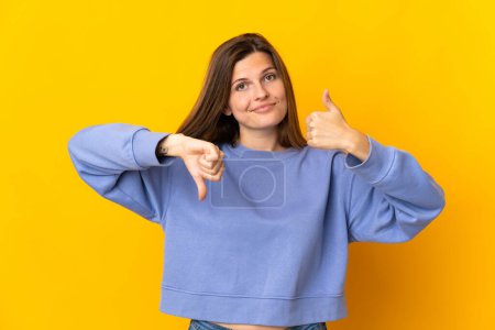 Photo for Young Slovak woman isolated on yellow background making good-bad sign. Undecided between yes or not - Royalty Free Image