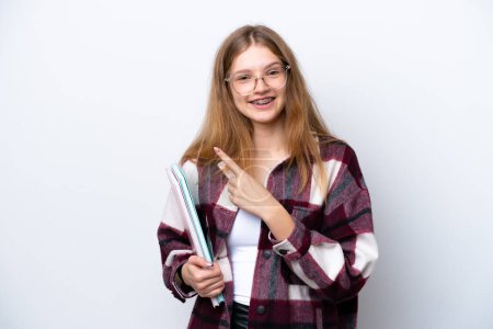Téléchargez les photos : Adolescent étudiant russe fille isolé sur blanc fond pointant vers l 'côté pour présenter un produit - en image libre de droit
