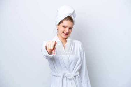 Téléchargez les photos : Adolescente russe dans un peignoir isolé sur fond blanc pointant devant avec expression heureuse - en image libre de droit