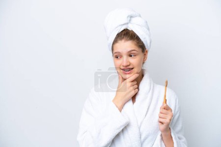 Foto de Adolescente rusa chica cepillarse los dientes aislados sobre fondo blanco pensando en una idea y mirando al lado - Imagen libre de derechos