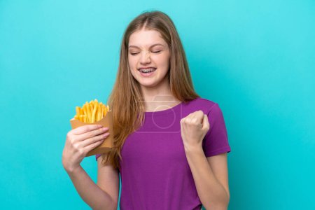 Photo for Teenager Russian girl catching french fries isolated on blue background celebrating a victory - Royalty Free Image
