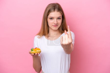 Photo for Teenager Russian girl holding a tartlet isolated on pink background doing coming gesture - Royalty Free Image