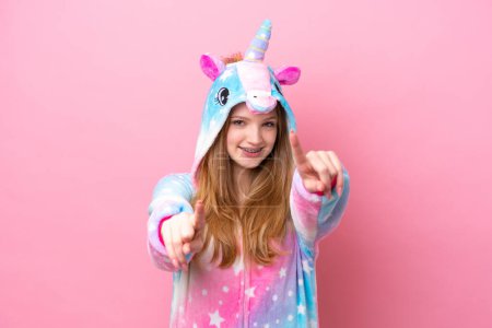 Foto de Adolescente rusa chica con unicornio pijama aislado en rosa fondo señala dedo en usted mientras sonríe - Imagen libre de derechos