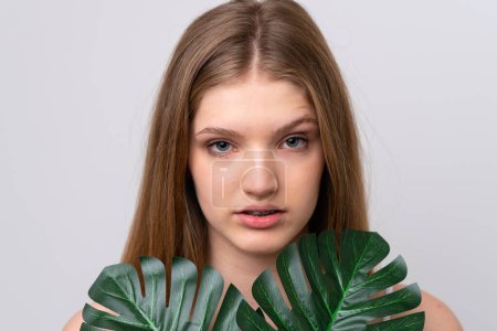 Téléchargez les photos : Adolescente russe isolée sur fond blanc tenant une feuille de palmier. Gros plan portrait - en image libre de droit